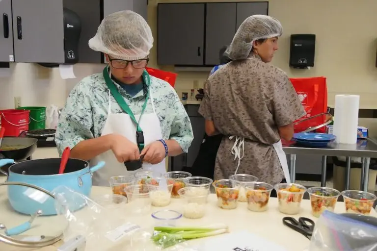 a youth fills a line of cups with samples of a dish he's prepared for a cooking contest