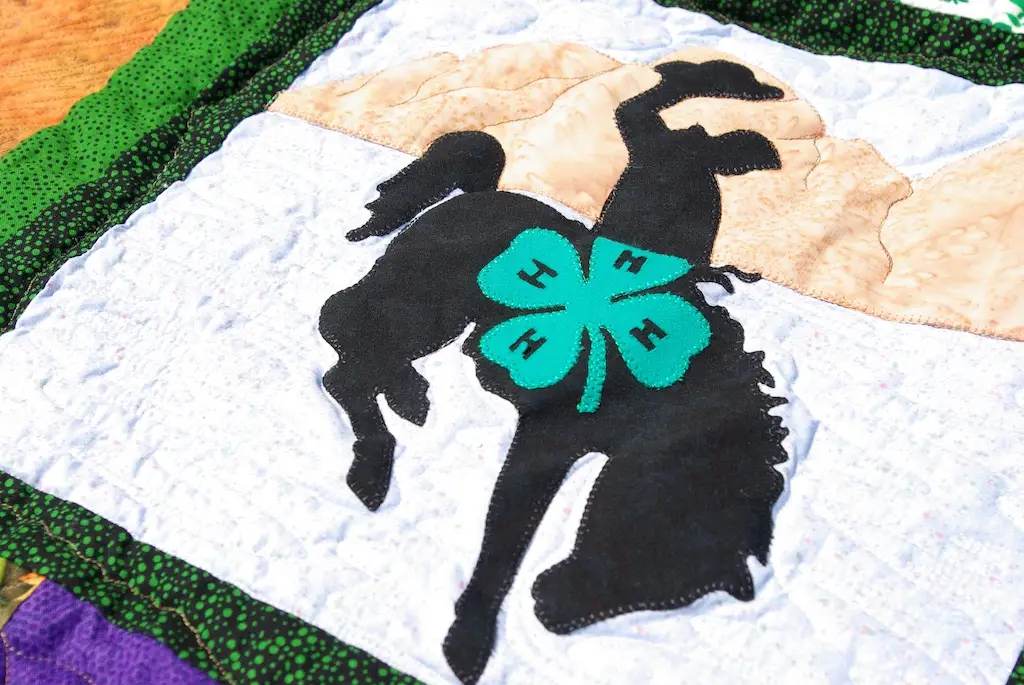 close up of a quilt with the 4-H logo inside the Wyoming steamboat logo