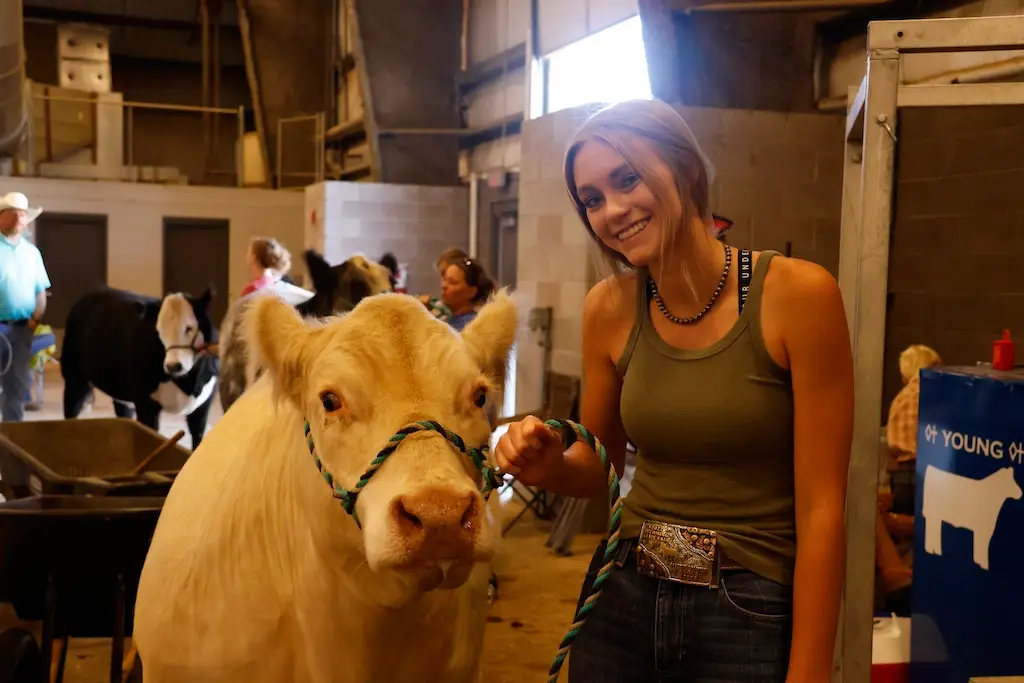 a woman smiles while holding the halter of her steer