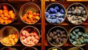 a rainbow of colored yarn displayed in buckets on a wall