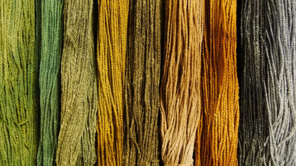 closeup of skeins of yarn hanging vertically in a pattern ranging in color from gree to brown