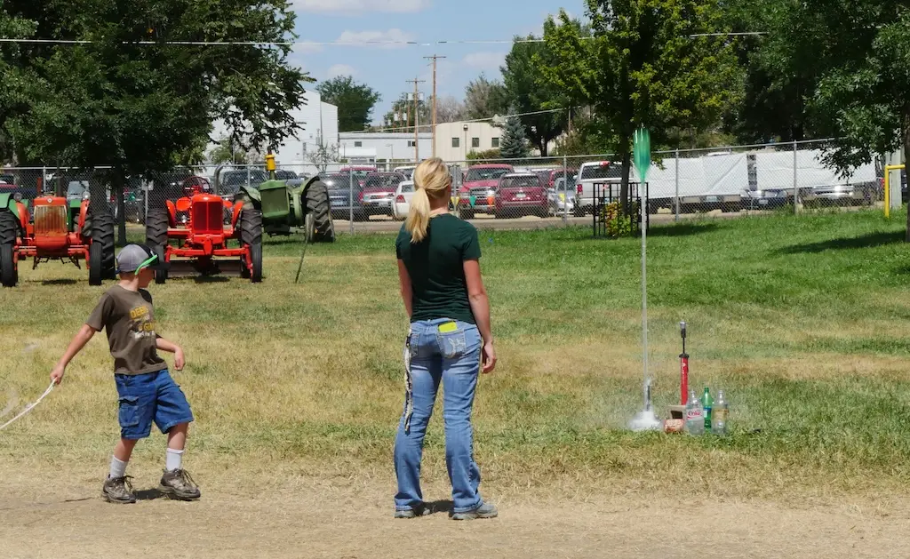 a youth launches a water powered 2 liter bottle rocket while an adult leader stands nearby