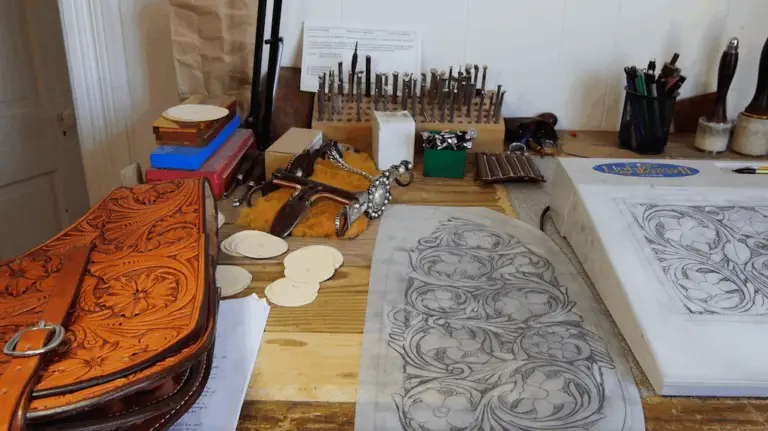 a leather working bench with tools a leather pouch and patterns drawn on velum