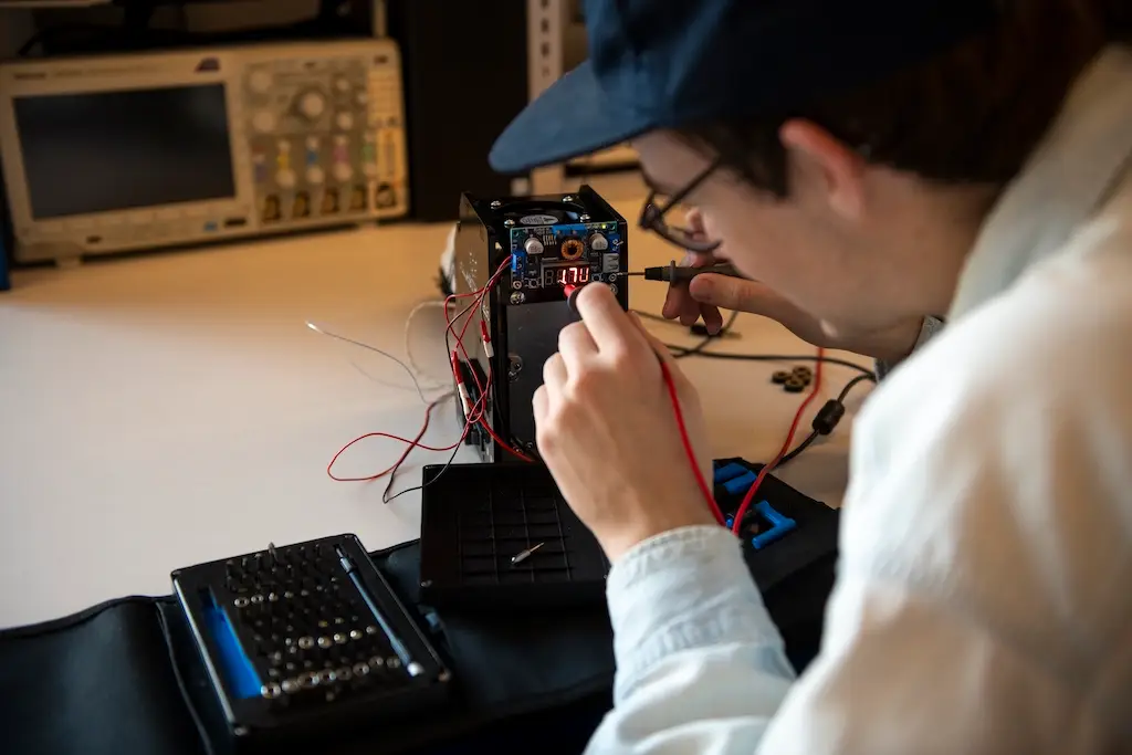 we look over a person's shoulder at a piece of electronic equipment they are manipulating with probes