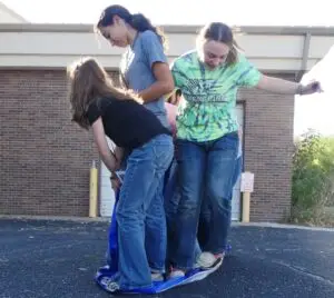 a group of young people work hard to balance on a folded tarp
