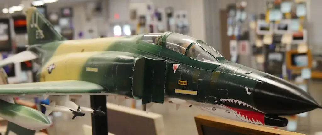 a model of a fighter jet painted in a camouflage pattern displayed at fair