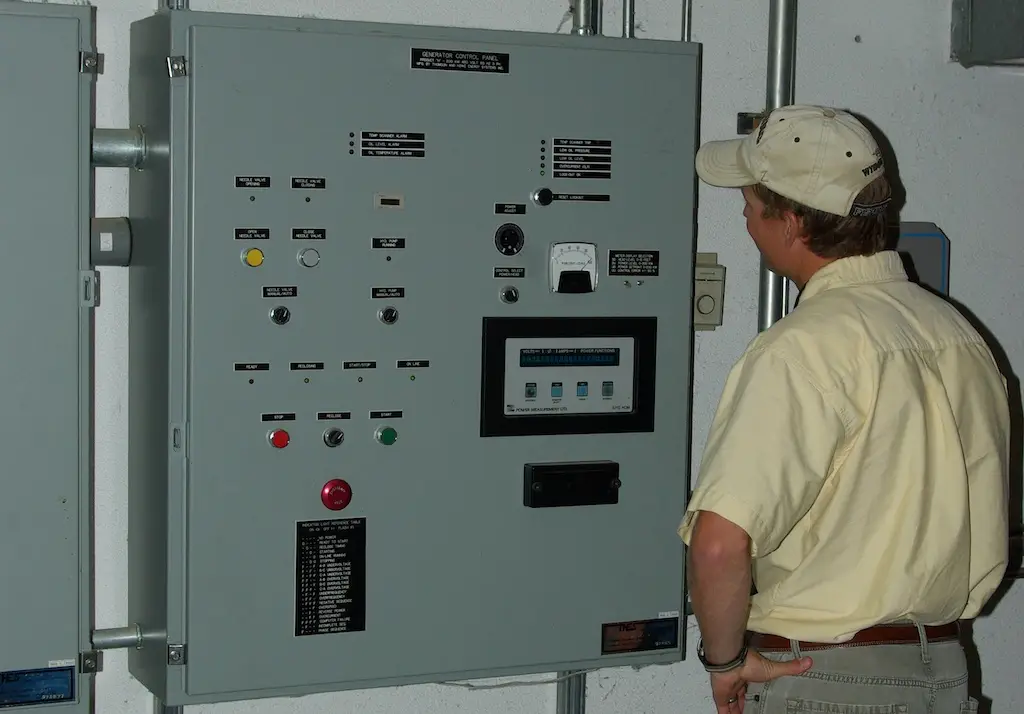 seen from behind a person looks at an electrical panel on a wall